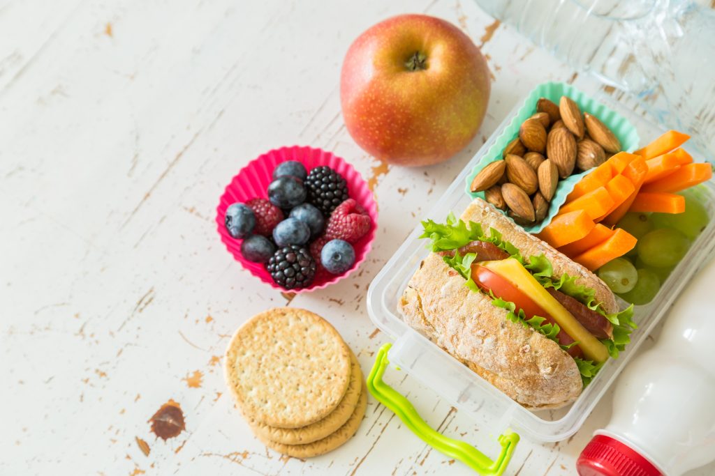 Healthy school lunch with fruit, a sandwich, nuts and vegetables