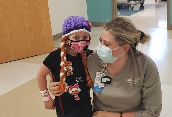 Harper takes a photo with her Child life specialist, Sam, both wearing masks