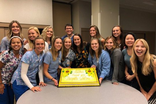 Student nurse interns pose around a cake at the end of their 2019 internship.