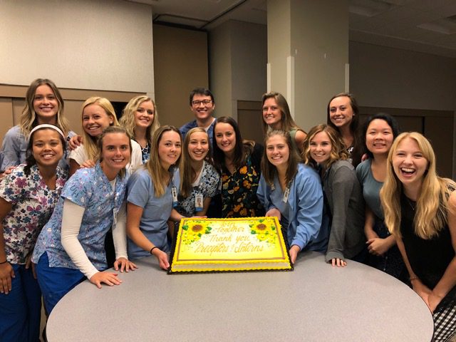 Student nurse interns pose around a cake at the end of their 2019 internship.