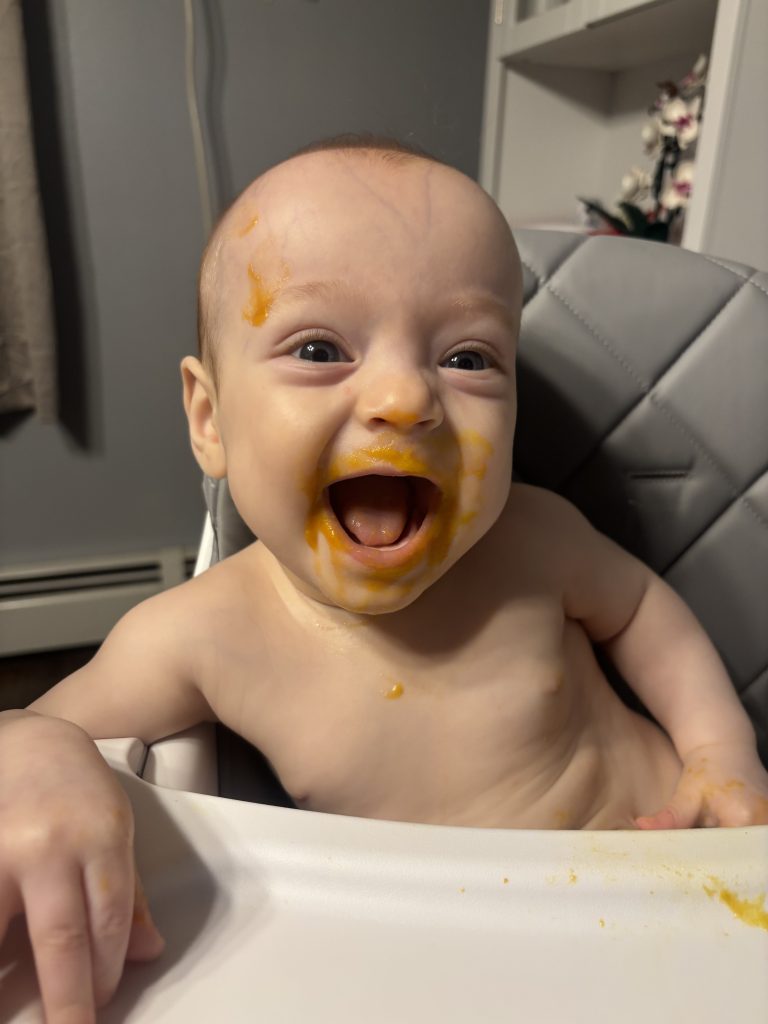 Owen smiles at the camera with food smeared on his face.