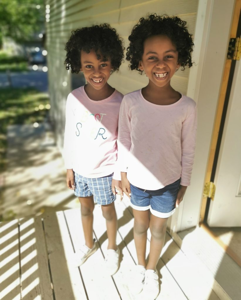 The twins standing outside smiling
