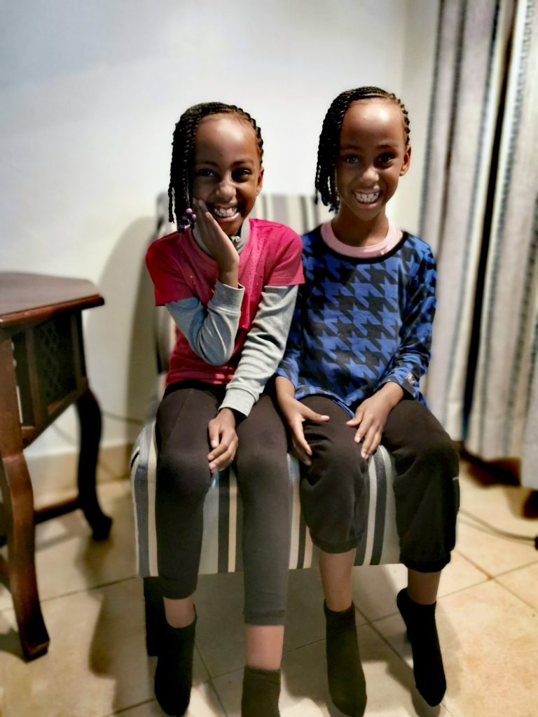 Twins sitting on one chair smiling
