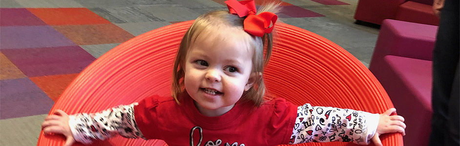 Margaret in a red chair at two-years-old