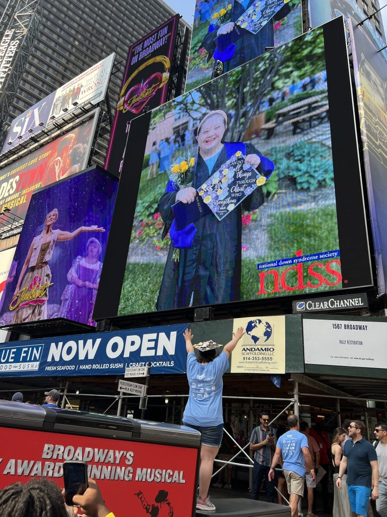 Elly's high school graduation photo was one of the photos displayed in Times Square in New York City on September 9, 2023 as part of the annual National Down Syndrome Society (NDSS) Times Square Video presentation.