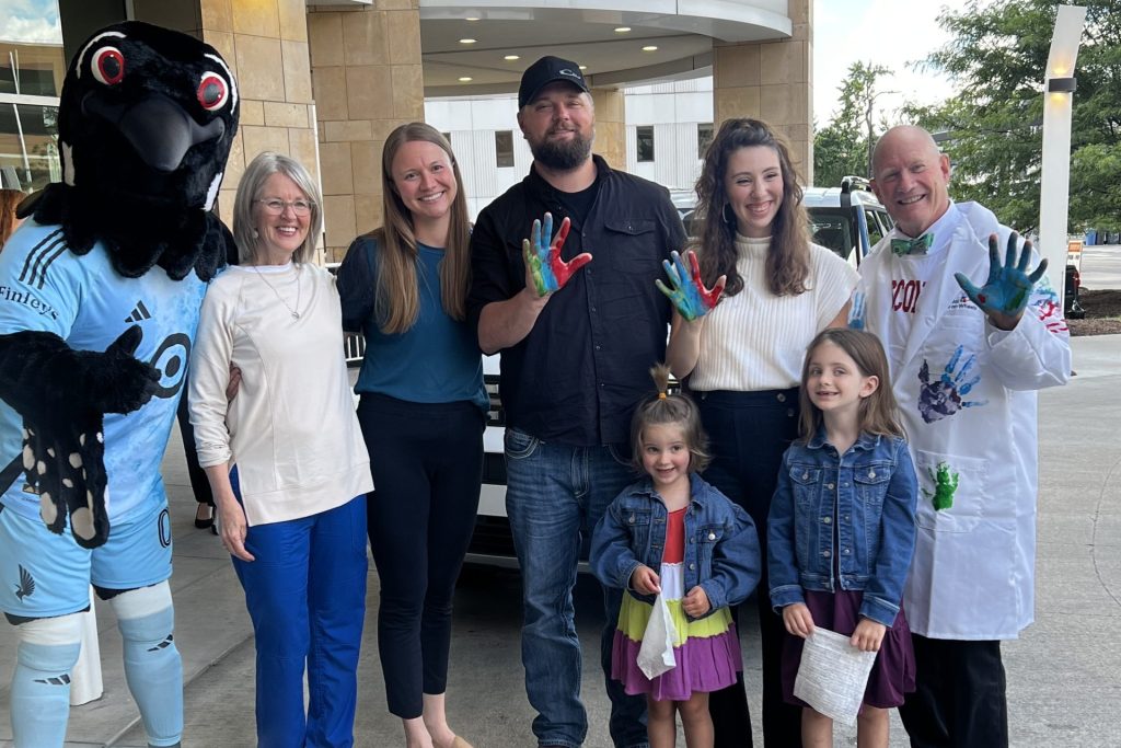 Dr. Stuart winter poses with a patient family and the Minnesota United mascot.