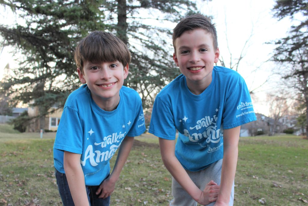 Two kids with Walk for Amazing t-shirts on outside smiling