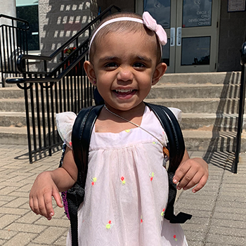Iraa with a backpack on in a pink dress