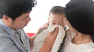 Parents and baby blowing nose