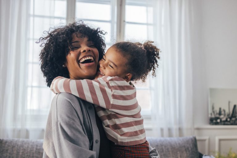 Daughter hangs on to mom as they laugh at home