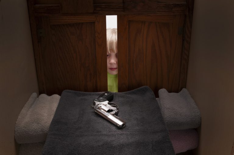 Child peeking into cabinet with gun.