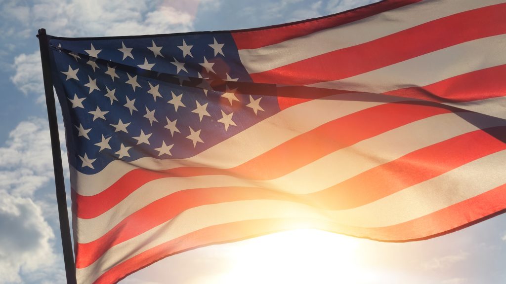 Close up American flag waving in the wind against sunset.