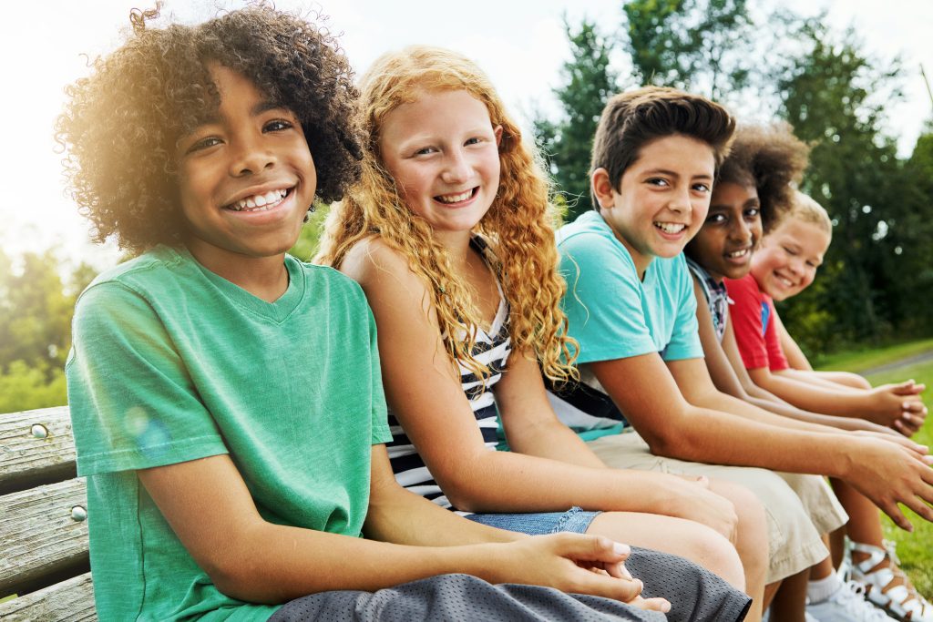 Portrait of a group of diverse and happy kids hanging out together outside