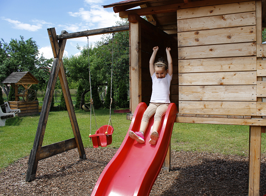 Young girl going down a slide in her back yard