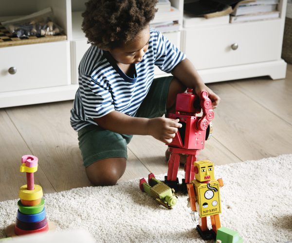 Little boy playing with a robot at home