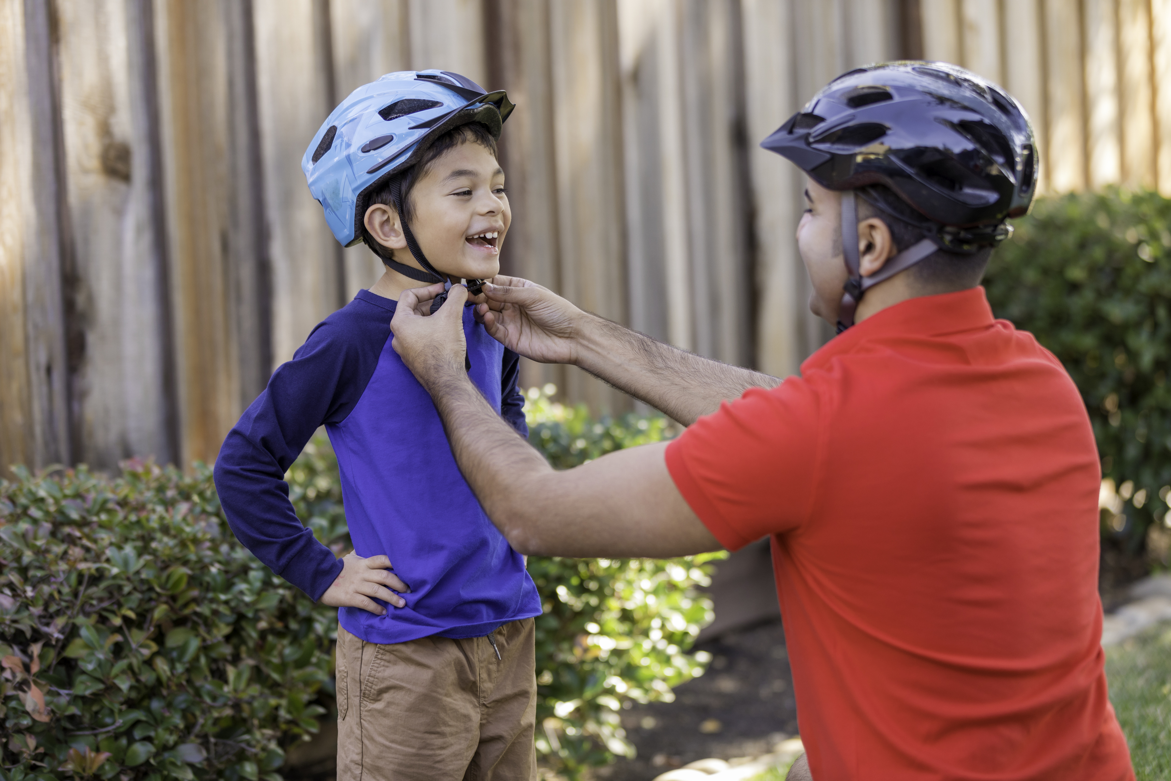 Father helping his son put on his bike helmet