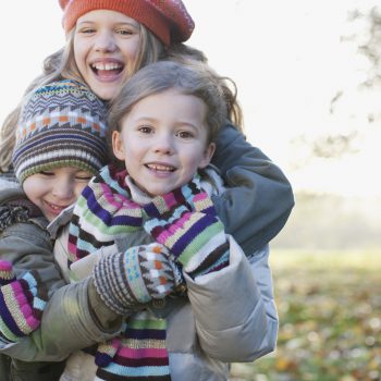Playful children smiling outdoors with hats