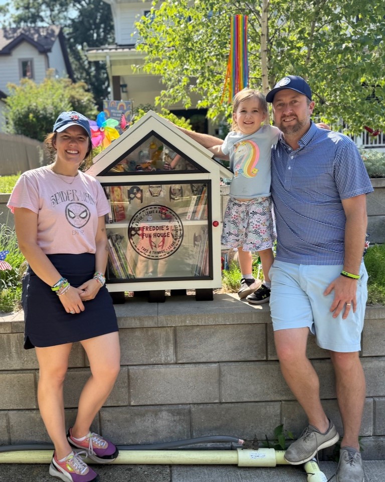 Lauren, Hattie and Mike standing next to Freddie's lending library.