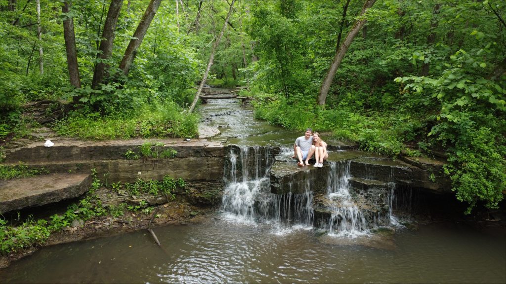Luke with his girlfriend sitting by a river during a camping trip.