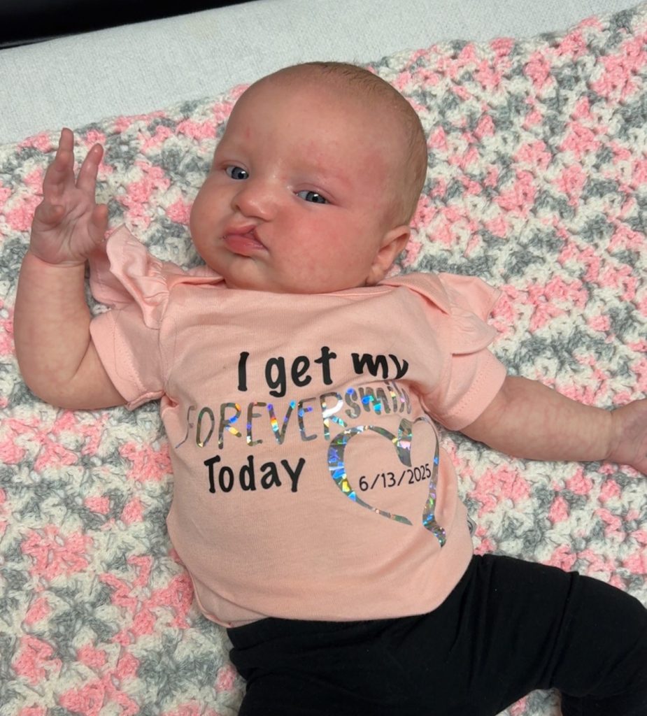 Luna wearing a onesie that reads 'I get my forever smile today'