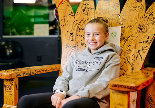 Kylie sitting on a giant chair smiling