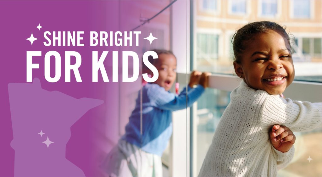 Shine bright for kids. 2 kids smiling and looking out the hospital hallway window