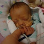 Madeline in the NICU holding her parent's finger