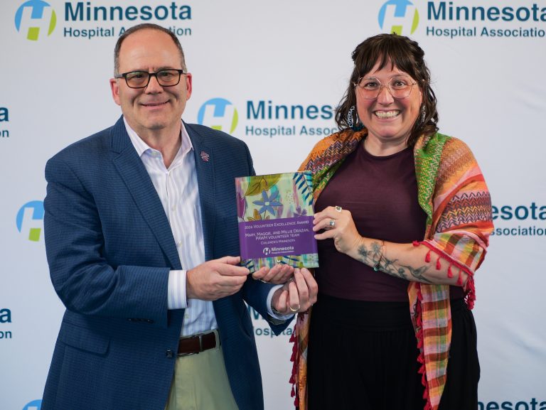 John Harding, executive vice president and chief operating officer at Children's Minnesota, and Annie Dressen, family resource and volunteer coordinator, hold the Minnesota Hospital Association's 2026 Volunteer Excellence Award. Dressen accepted the award on behalf of Children's Minnesota's PAWH volunteer team.
