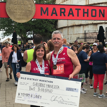 Brad and Barb Turgeon at the end of their race holding a check for Children's Minnesota