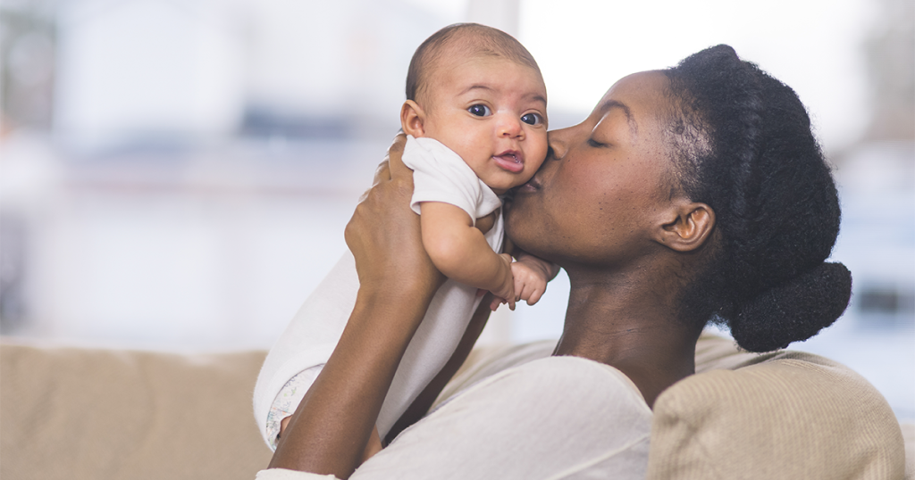 Mom at home kissing their new baby