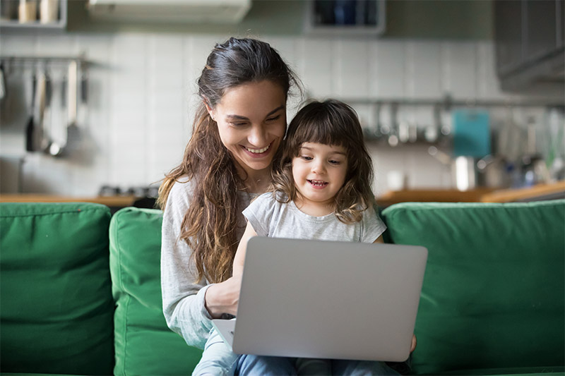 Mom on computer with daughter at home.