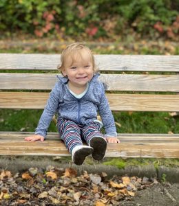 Morgan sits smiling on a park bench