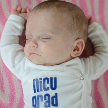A baby in a NICU Grad onesie