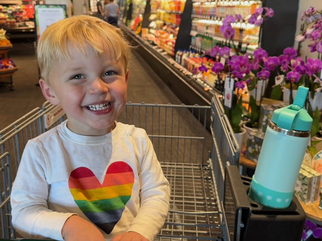 Ollie sitting in a grocery cart and smiling