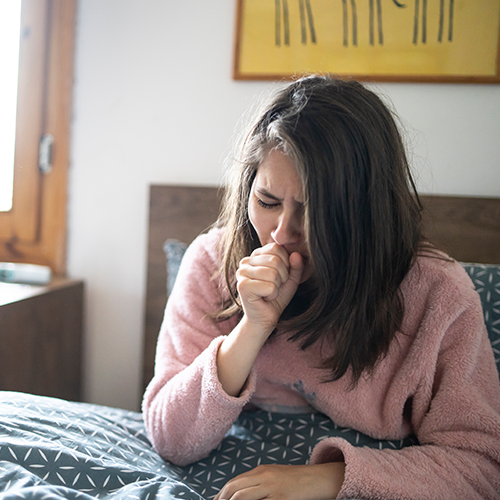 Teen coughing in bed with whooping cough