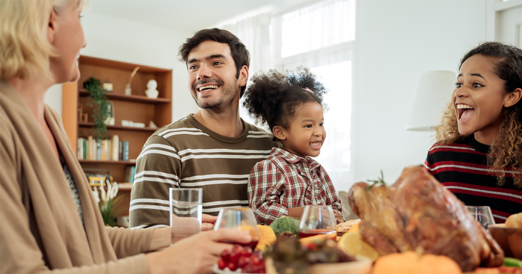 Toddler girl sits at Thanksgiving meal table with dad
