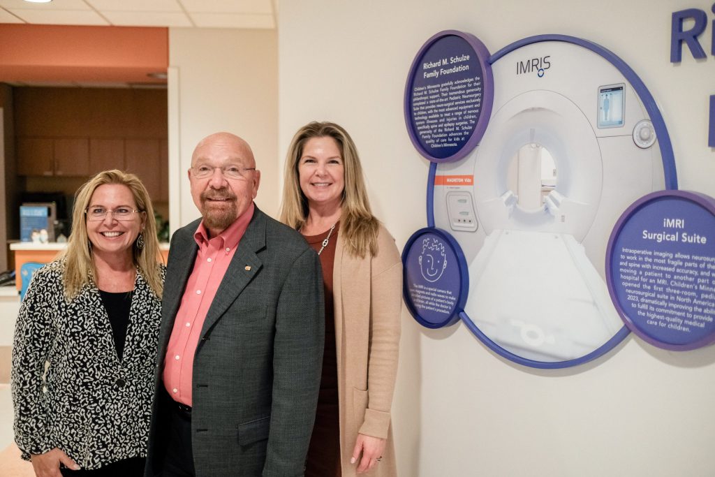 Three people stand next to a sign about the iMRI