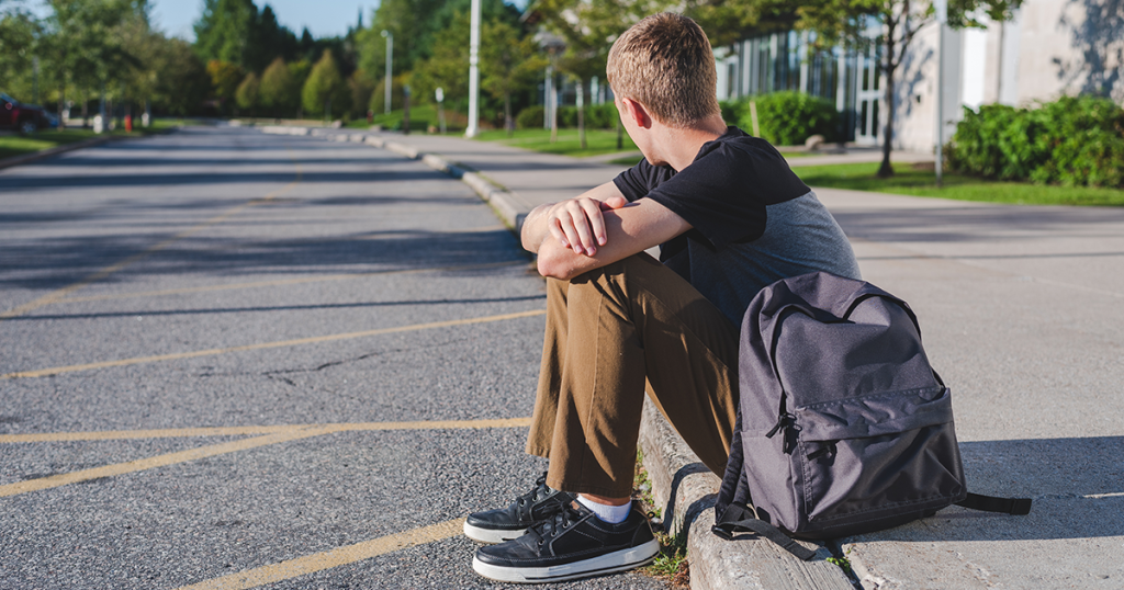 sad teen boy with backpack
