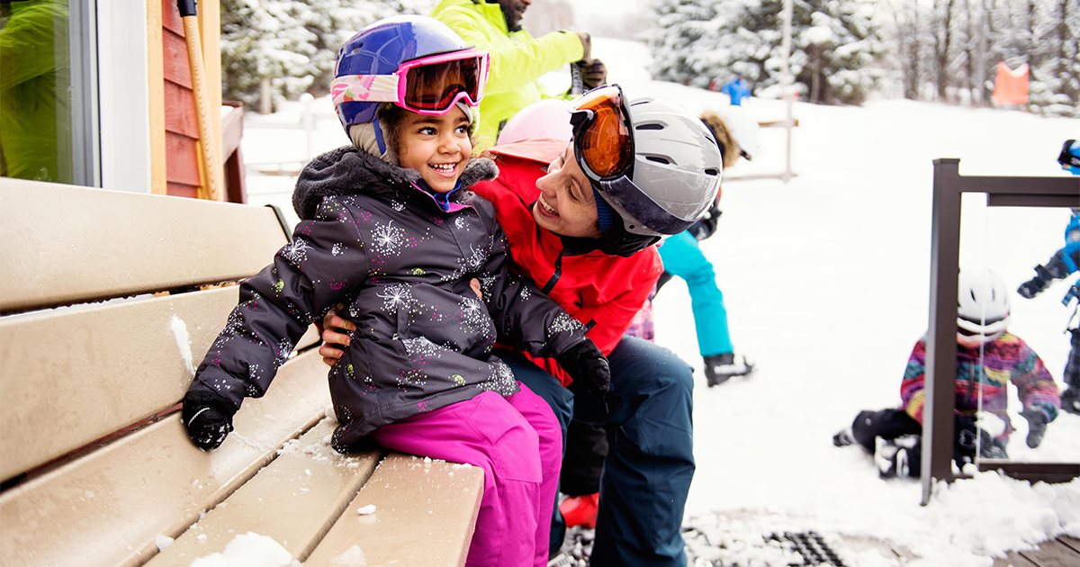 mother helping daughter get ready to ski