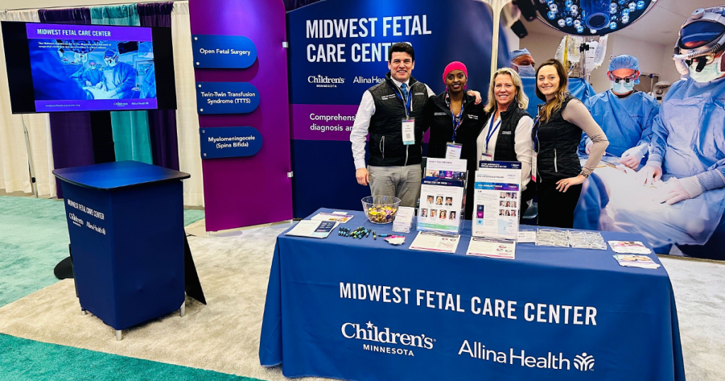A group of people at the Midwest Fetal Care Center booth at SMFM 2023.