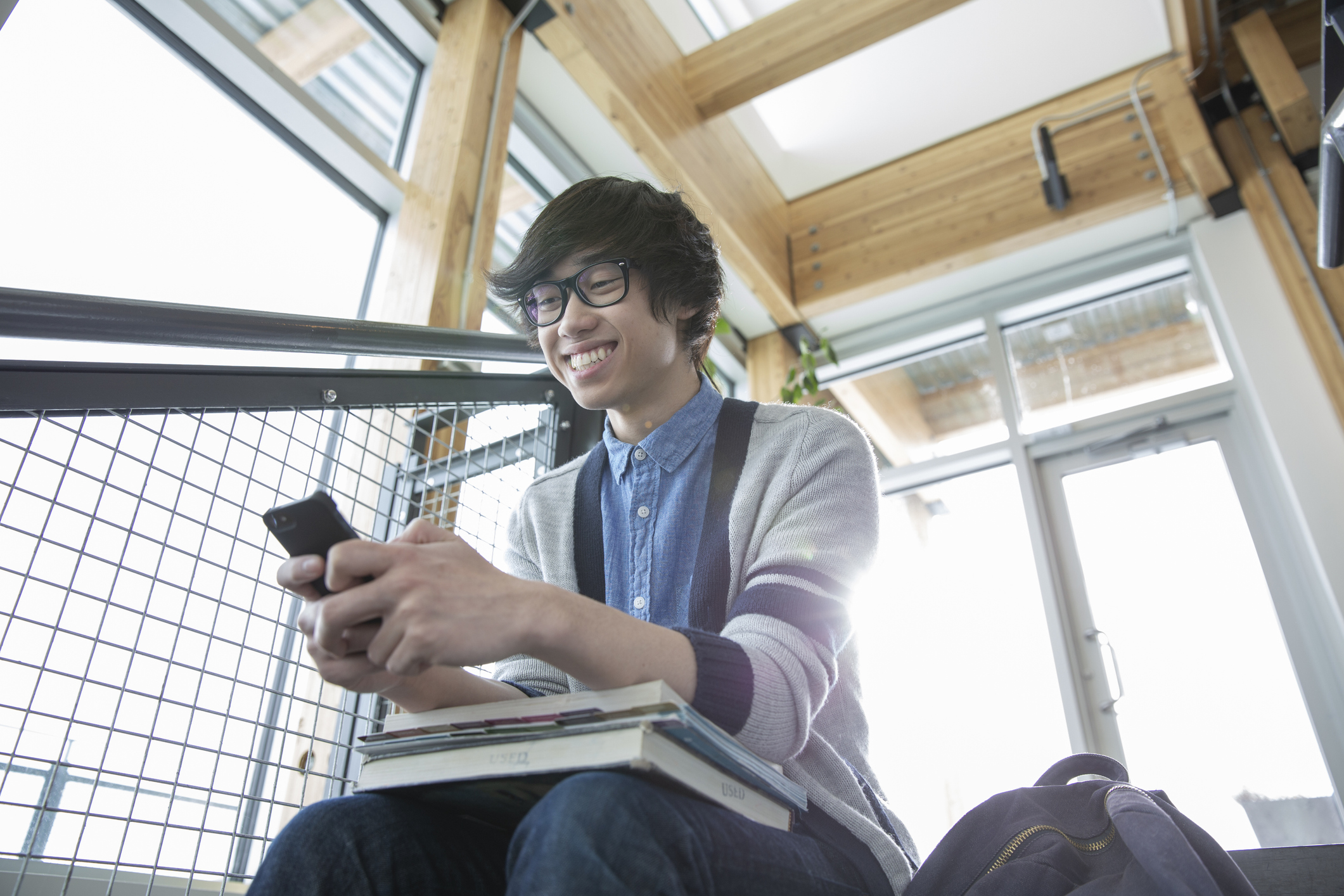 Teenage boy on his phone at school sitting on the steps
