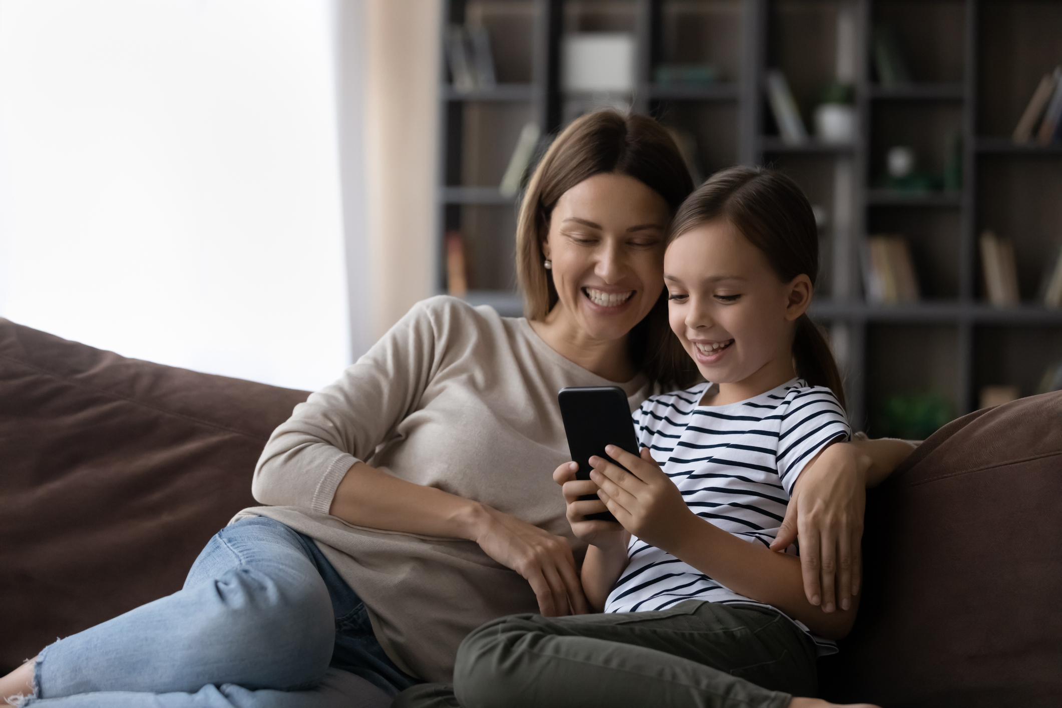 Mom and daughter on the couch looking at the daughter's phone
