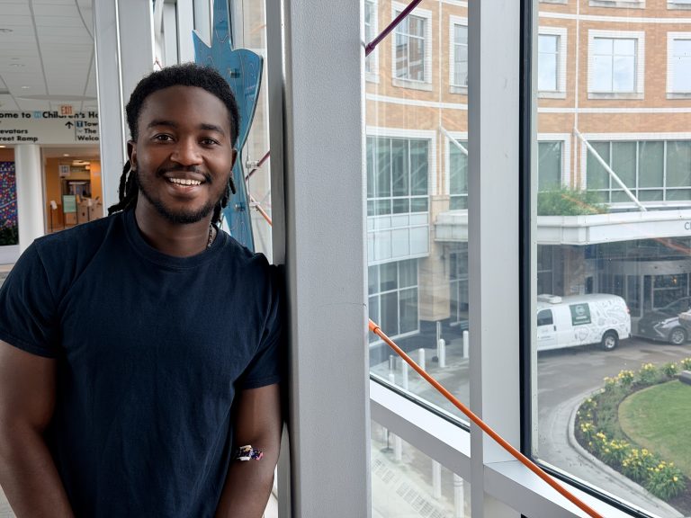 Stephen, adolescent and young adult cancer survivor, posing in the skyway of Children's Minnesota hospital in Minneapolis.