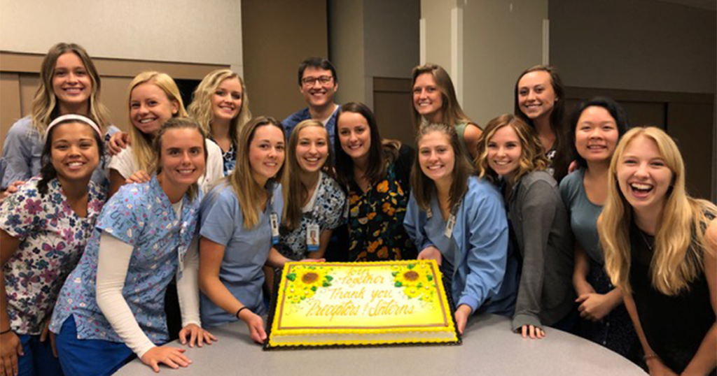 Student nurse interns pose around a cake at the end of their 2019 internship.