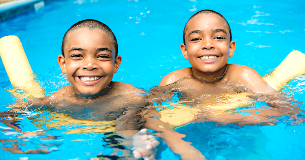 Twin adolescent boys swimming in an outdoor pool