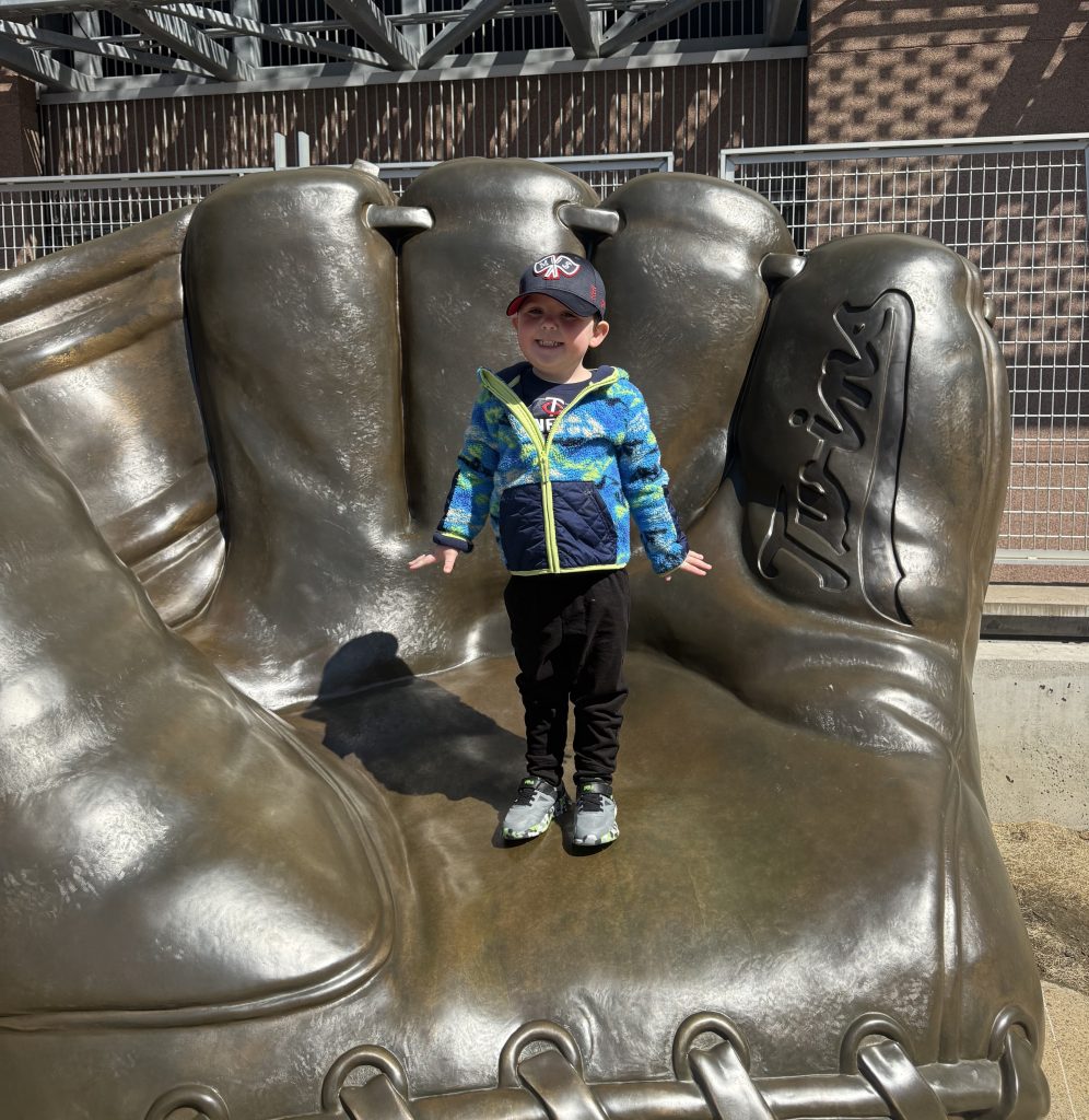 William standing in a baseball glove monument outside Target Field, the ballpark of the Minnesota Twins.
