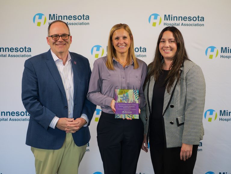 Terasa Smith accepts the Minnesota Hospital Association's 2026 Community Benefit Award on behalf of Project ADAM Minnesota, with Children's Minnesota leaders John Harding and Brittany Glauser standing alongside her.