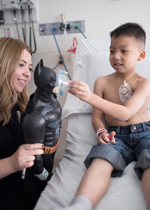 A child life specialist explaining a medical procedure with a patient at his bedside