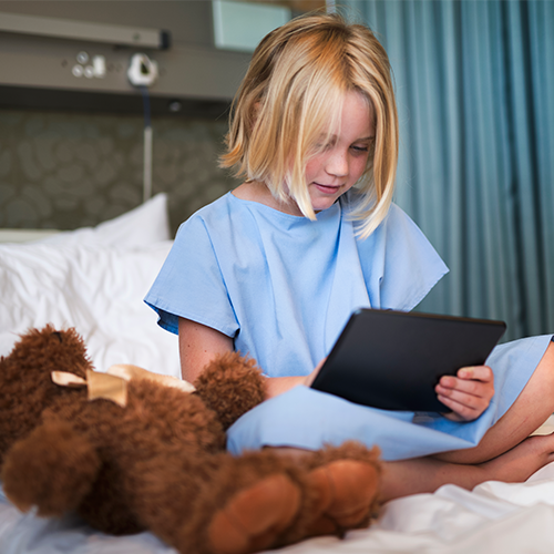 Sick child in hospital using iPad.