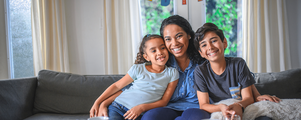 Mom laughing on couch with son and daughter